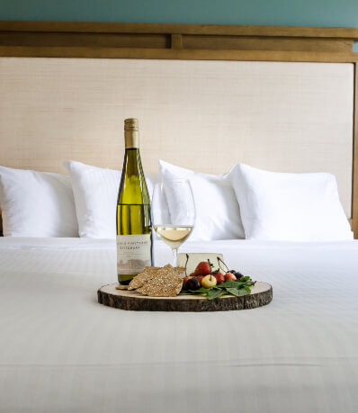 Cheese tray & wine bottle on bed.
