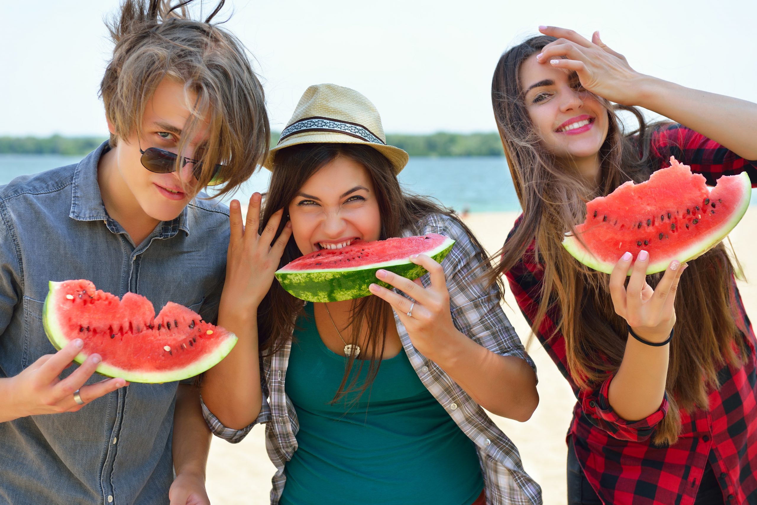 Three people wat watermelon on Osoyoos beach