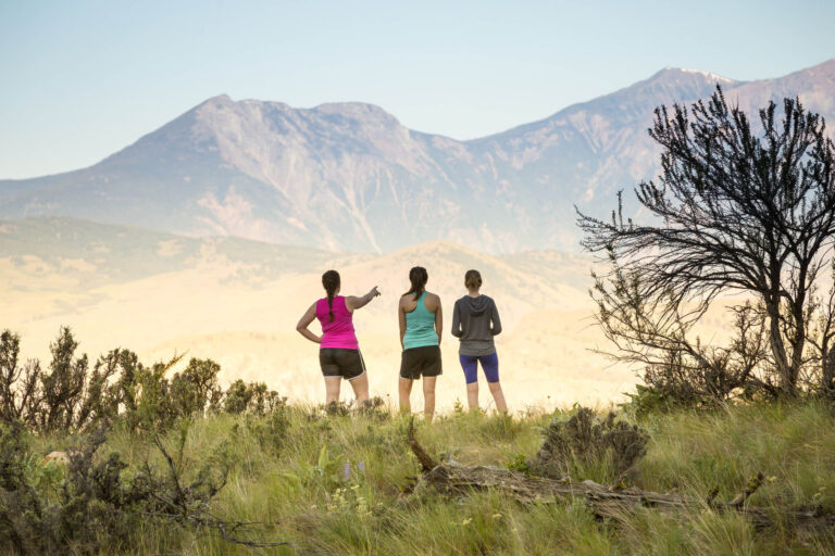Three hikers look out towards the mountainous horizon ahead.
