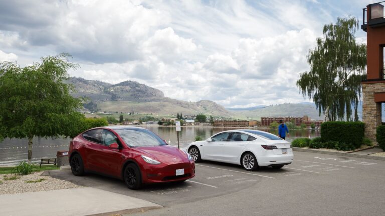Two electric vehicles parked outside of an Osoyoos Hotel.