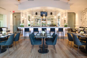 15 Park Bistro dining room with navy chairs, marble tables and a backlit bar in Osoyoos