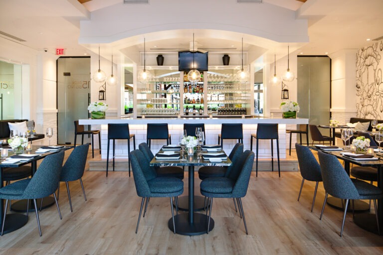 15 Park Bistro dining room with navy chairs, marble tables and a backlit bar in Osoyoos
