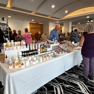 Handmade soap and body care products displayed on a long table at the indoor Osoyoos Farmers Market inside the Watermark Beach Resort Ballroom