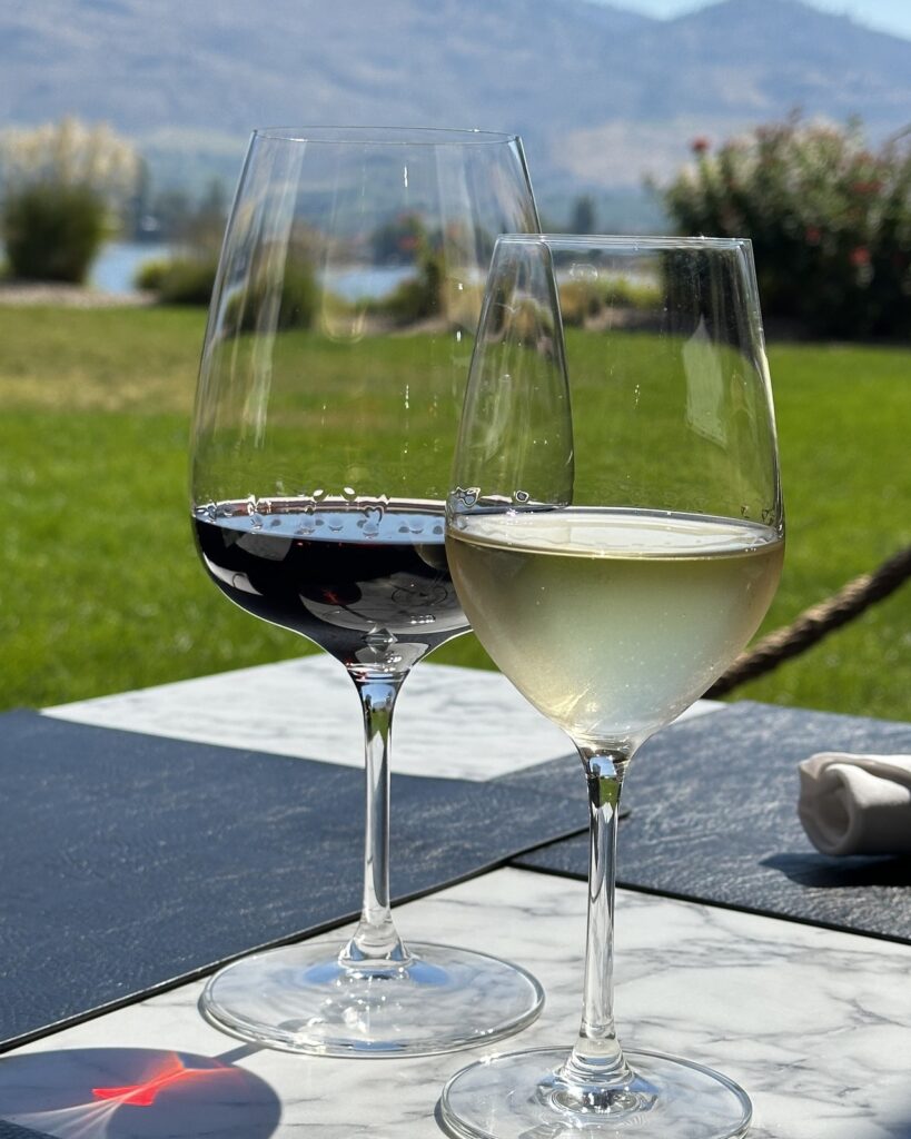 Glasses of red and white wine on the 15 Park patio at Watermark Beach Resort with Osoyoos Lake behind