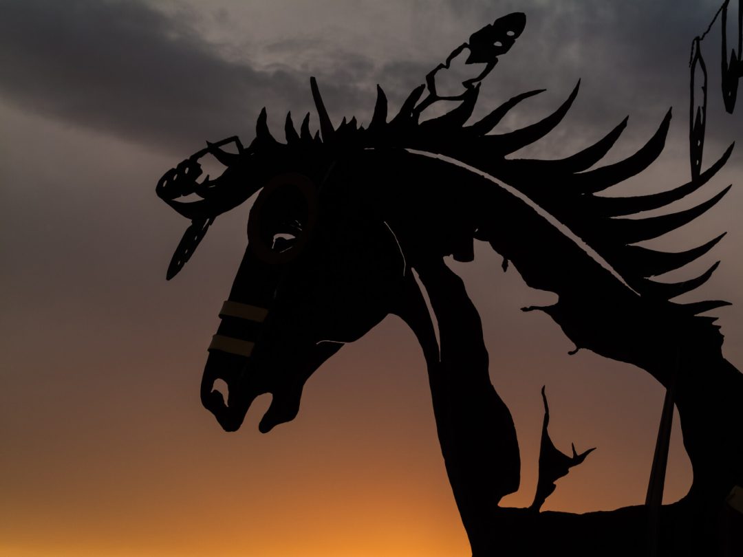 A silhouette of an Indigenous horse statue at sunset.